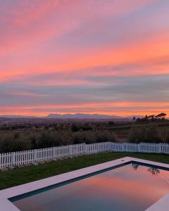 a swimming pool with a sunset in the background at Olea b&b in Montecosaro