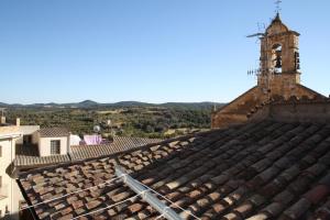 un ancien toit en carrelage d'un bâtiment avec une tour d'horloge dans l'établissement Apartamento Benabarre, Huesca, à Benabarre
