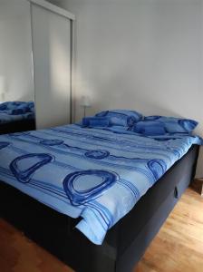 Una cama con mantas azules y almohadas. en SP Apartmani FREE PARKING en Vranje