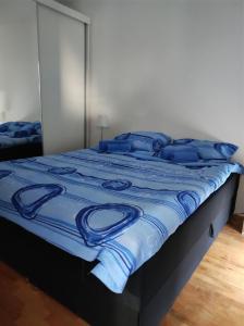 een bed met blauwe dekens en kussens erop bij SP Apartmani FREE PARKING in Vranje