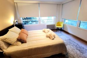 a bedroom with a large bed and a yellow chair at Completo apartamento a un paso de La Concha in Donostia-San Sebastián