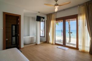 a bedroom with a bed and a tub and a view of the beach at Diamond Beach Resort in Ko Samed
