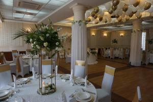 a banquet hall with white tables and chairs and flowers at Aviator Hotel Restauracja & SPA in Pabianice