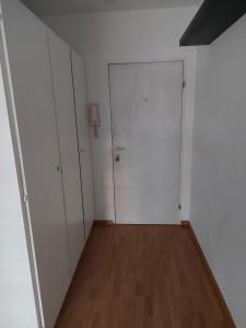 ein leeres Zimmer mit einer weißen Tür und einem Holzboden in der Unterkunft Kleine Apartment im Zentrum Bern in Bern