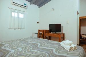 um quarto com uma cama, uma televisão e uma secretária em Palo Rosa Lodge em Puerto Iguazú