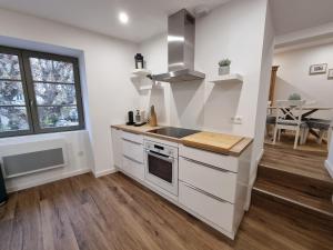 a kitchen with white cabinets and a counter top at HOME ET HOLIDAY Le Petit Verdot in Viviers +3 photos