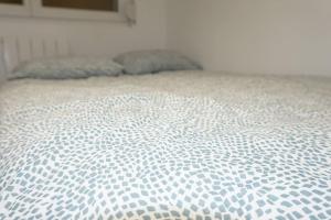 uma cama branca com uma colcha azul e branca em Coquet STUDIO TOUT ÉQUIPÉ CENTRE VILLE WIFI 2PERS em Saint-Quentin