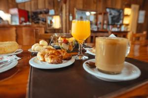 stół z talerzami jedzenia i szklanką soku pomarańczowego w obiekcie Palo Rosa Lodge w mieście Puerto Iguazú