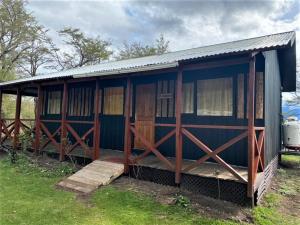 a blue house with a porch on the grass at Departamentos 8va Maravilla in Torres del Paine