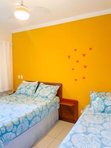 1 dormitorio con 2 camas y pared amarilla en Flat 1 Dorm. Maresias Praia&Lazer& Ar&Piscina F3 en São Sebastião