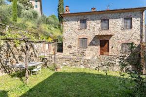 een stenen huis met een picknicktafel in de tuin bij Villa Pera by Nicola Real Estate in Corsanico-Bargecchia