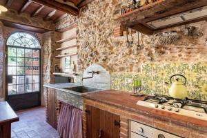 een keuken met een stenen muur en een fornuis bij Villa Pera by Nicola Real Estate in Corsanico-Bargecchia