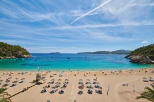 a beach with umbrellas and people in the water at El Somni Ibiza Dream Hotel by Grupotel in Sant Joan de Labritja +26 photos