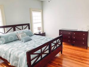 a bedroom with a large bed and a dresser at The Gator Manor – 6 Bedrooms Walk to UF / Stadium in Gainesville