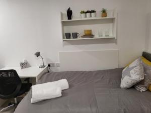 a bedroom with a bed with a desk and a chair at Theatre House Apartment 13 in Coventry