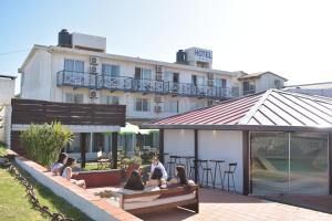 un grupo de personas sentadas en un banco frente a un hotel en Hotel Palma de Mallorca en La Paloma