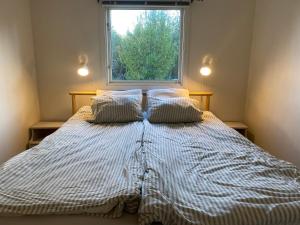 1 cama con 2 almohadas en un dormitorio con ventana en Tjänstebostaden på Storöns bondgård, en Otterbäcken