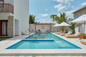 uma piscina num quintal com cadeiras e guarda-sóis em Aiolos Hotel & Discoveries em Praia do Preá