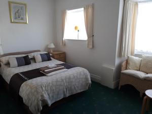 a bedroom with a bed and a chair and a window at The Craigmore in Blackpool