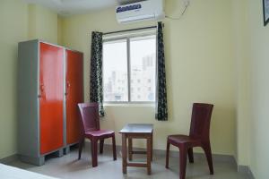 a room with two chairs and a table and a window at Hotel Yellow Bells in Hyderabad