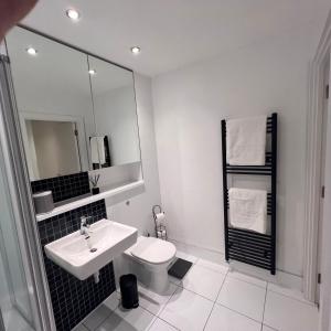 a white bathroom with a sink and a toilet at K D Tower Lux Apartment in Hemel Hempstead