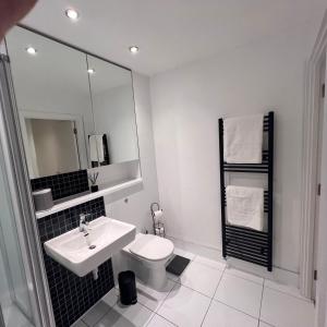 a white bathroom with a sink and a toilet at K D Tower Lux Apartment in Hemel Hempstead +12 photos