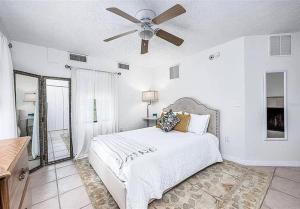 Un dormitorio blanco con una cama y un ventilador de techo. en Gator Den 6 Bedrooms Steps to UF, en Gainesville
