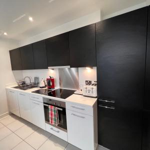 una cocina con armarios negros y electrodomésticos blancos en K D Tower Lux Apartment en Hemel Hempstead