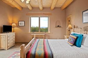 Schlafzimmer mit einem Bett, einem TV und einem Fenster in der Unterkunft Casa Cielo in Taos