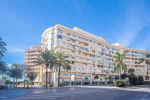 a large building with palm trees in front of a street at Deluxe Apartment on the First Line in Marbella