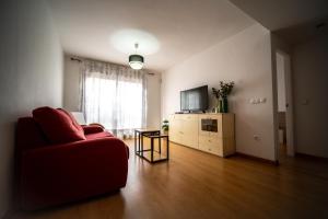 sala de estar con sofá rojo y TV en Orillas del Castillo, en Alicante