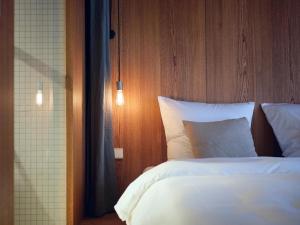 Schlafzimmer mit einem weißen Bett mit einem Kopfteil aus Holz in der Unterkunft ArtBau Designhotel in Waldkirch