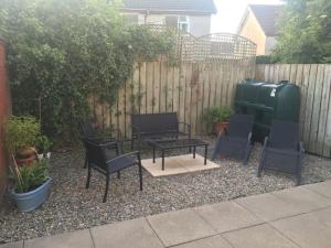 a patio with chairs and a table and a fence at Primrose Cottage, Bushmills - Cosy Self Catering Property in Bushmills