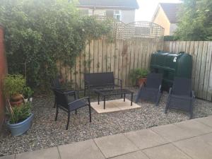 eine Terrasse mit Stühlen, einem Tisch und einem Zaun in der Unterkunft Primrose Cottage, Bushmills - Cosy Self Catering Property in Bushmills