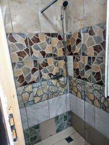 La salle de bains est pourvue d'une douche et d'un mur en pierre. dans l'établissement Front Garden Cabin Home with Terrace(Self Check-in), 