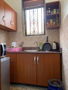 a kitchen with wooden cabinets and a sink and a window at MiniPalais Bukoto in Kampala