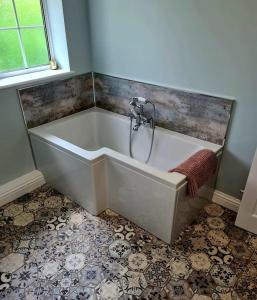 a white bath tub in a bathroom with a window at Stunning 2 bedroom cottage on the River Wensum in Earlham