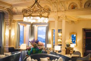 Le hall de l'hôtel est doté d'un lustre, de tables et de chaises. dans l'établissement Grand Hotel Kronenhof, à Pontresina