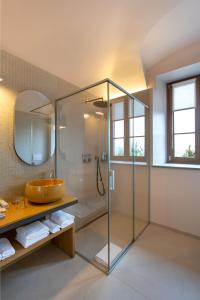 La salle de bains est pourvue d'une douche en verre et d'un lavabo. dans l'établissement Villaggio Narrante - Cascina Galarej, à Sorano