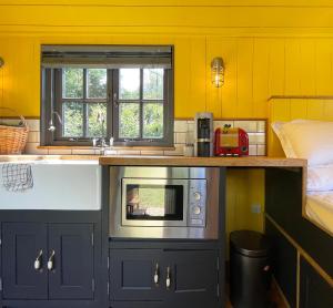 a kitchen with a sink and a microwave at Old King William Shepherd Huts and Private Hot Tubs in North Norfolk in Hunworth