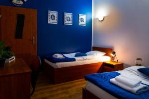 a room with two beds and a blue wall at Hotel Nenufar in Kościan