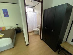 a bathroom with a black cabinet next to a toilet at Aracari Garden Hostel in Tortuguero