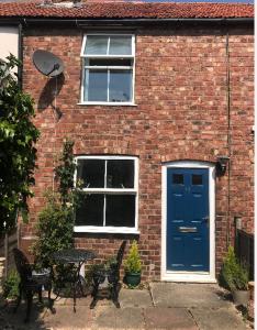 una casa de ladrillo con una puerta azul y un banco en Attractive 2 bed cottage in Hempton Fakenham, en Fakenham