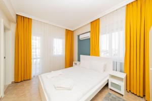 białe łóżko w pokoju z pomarańczowymi zasłonami w obiekcie Flat with Balcony and Shared Pool in Belek w mieście Belek
