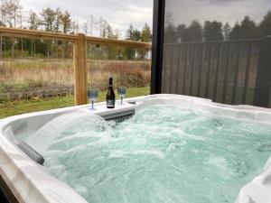 a hot tub with a bottle of wine and two glasses at Holicarrs - Gingerlily in Riccall