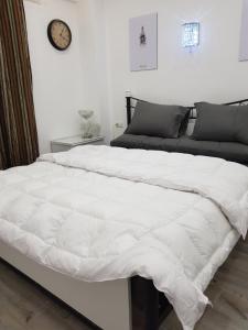 een groot wit bed in een slaapkamer met een klok aan de muur bij Flat 01 bed room. Sea Street. Hadaba Area. in Sharm El Sheikh