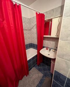 baño con cortina de ducha roja y lavamanos en Apartments D&D, en Požarevac