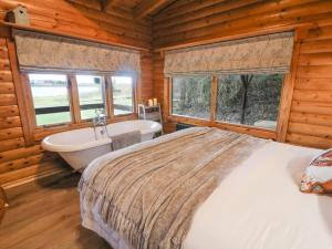 um quarto com uma cama grande, uma banheira e janelas em Whitemoor Lodge em Barnoldswick