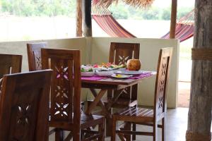 een houten tafel met stoelen en een bord eten erop bij Nirvaan Safari Lodge in Wilpattu