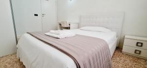 una camera da letto con un letto bianco e asciugamani di Locazione Turistica Gioia a Padova